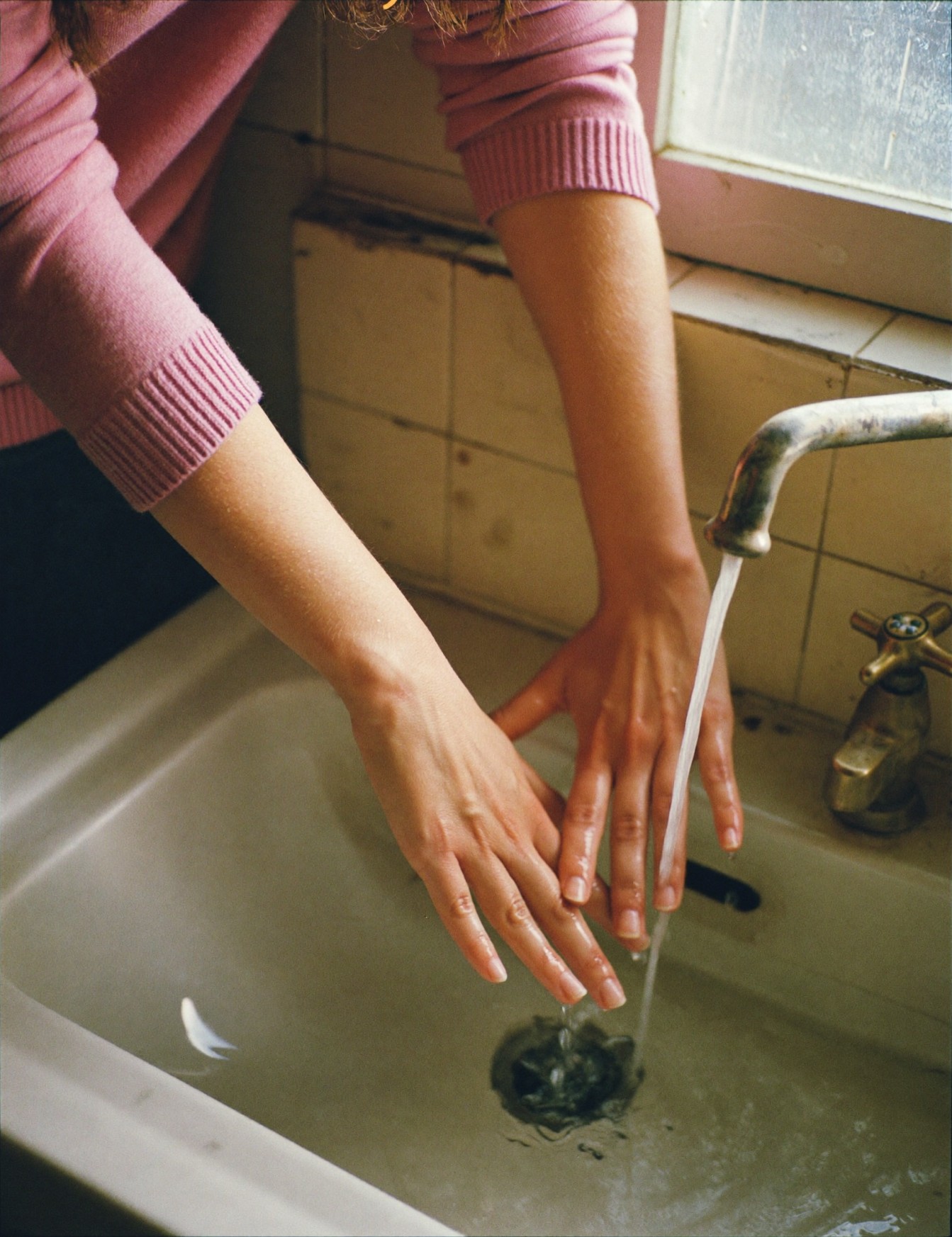 Mains rincées sous l'eau à un lavabo en céramique