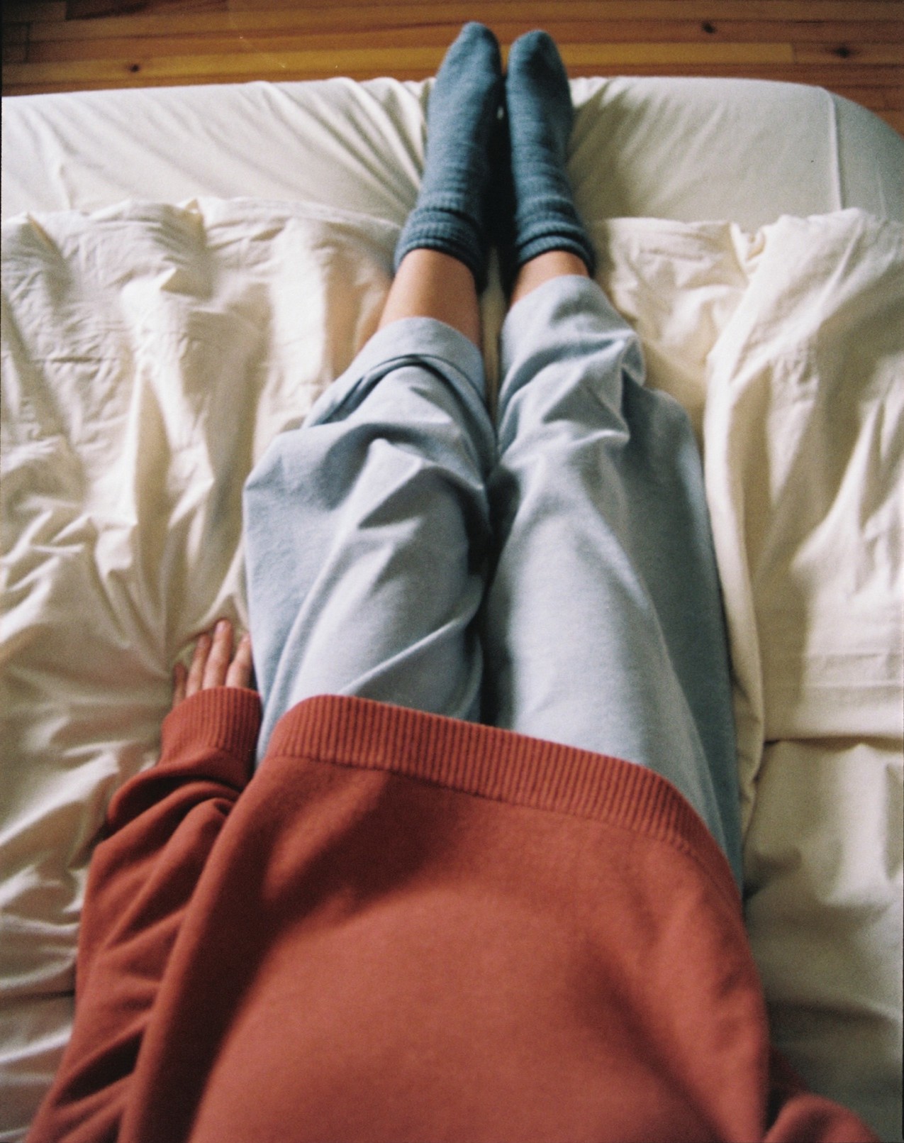 Vue de dessus, jambes en chaussettes étendues sur des draps froissés