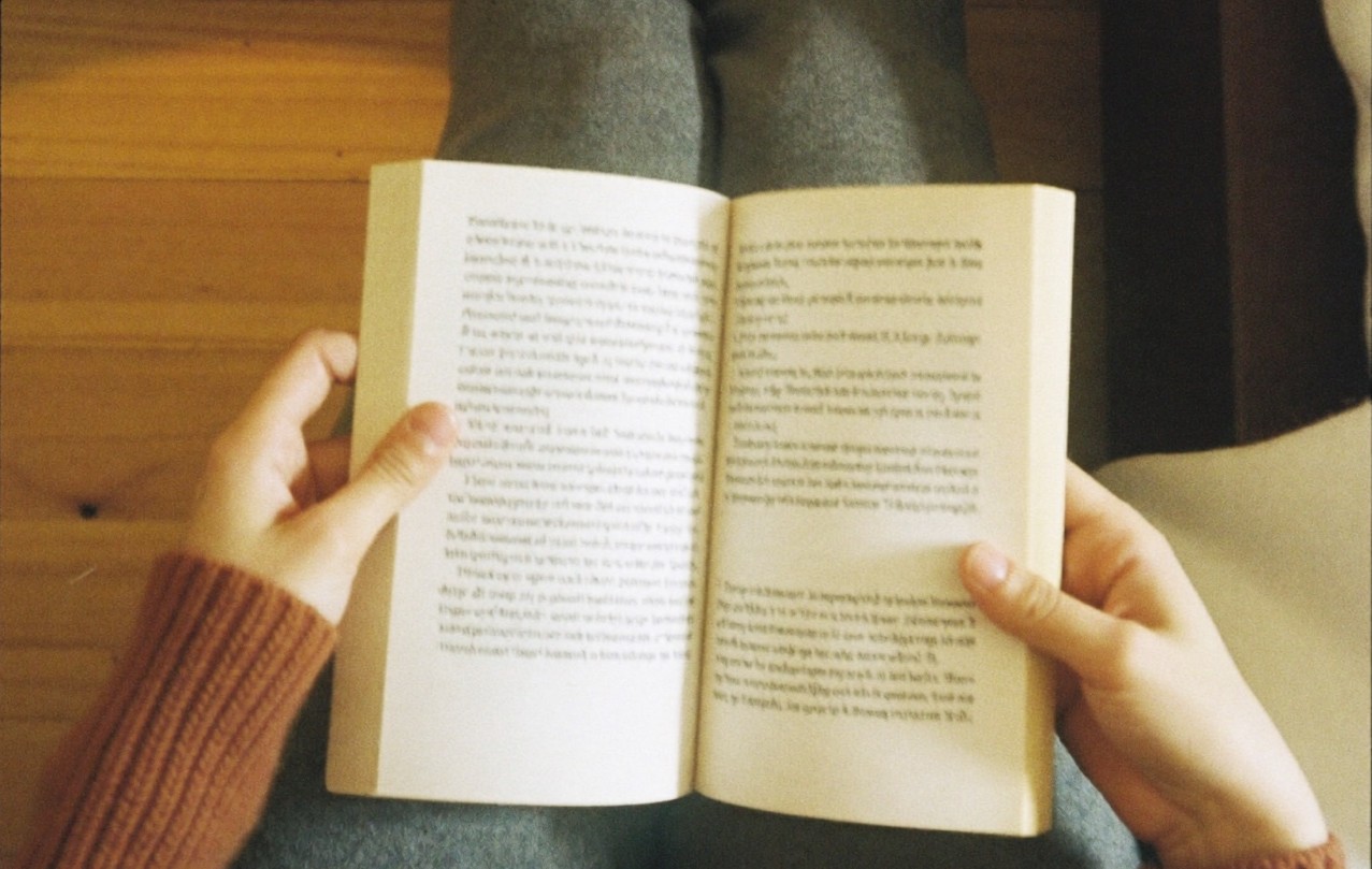 Vue de dessus, mains tenant un livre ouvert sur les genoux, lumière de lampe